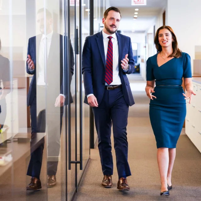 Two lawyers walking down a hallway in an office.