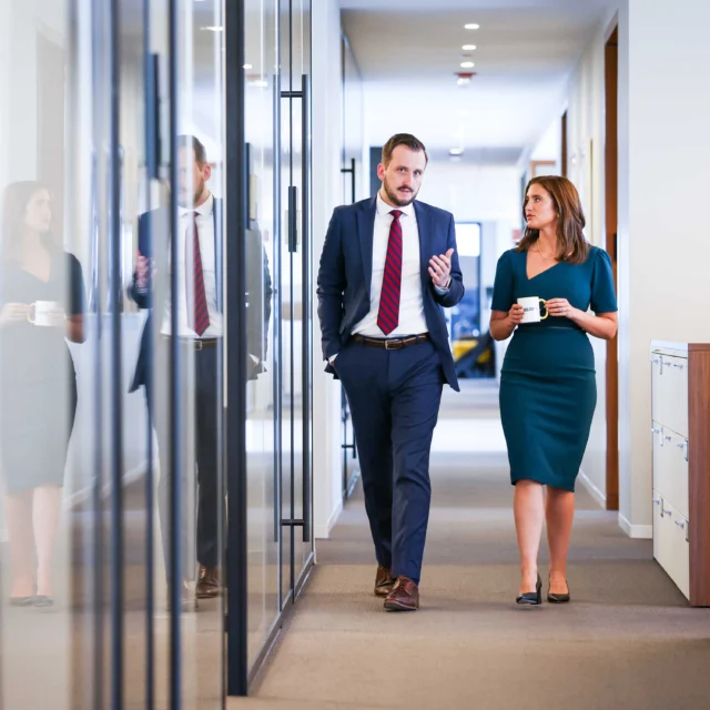 Two lawyers walking down a hallway in an office.